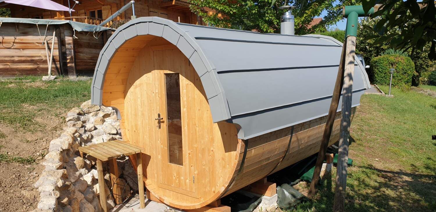 Installation d'un sauna en tonneau de bois dans le jardin.