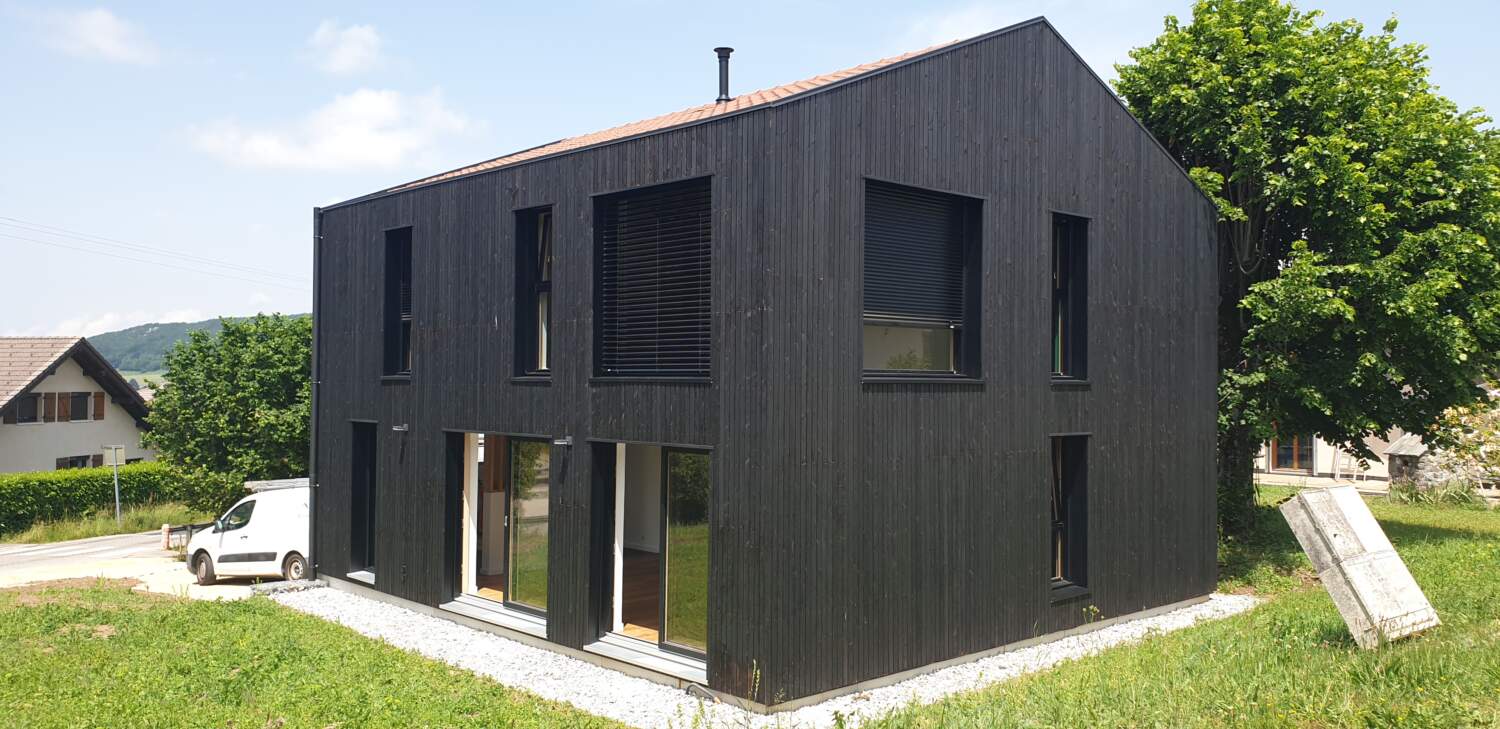 Construction de maison en bois moderne avec de grandes fenêtres.