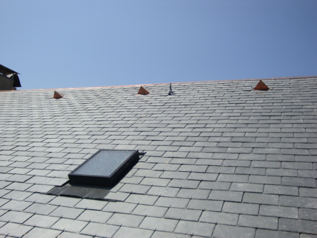 Travaux de couverture avec tuiles grises et installation de lanterneaux.